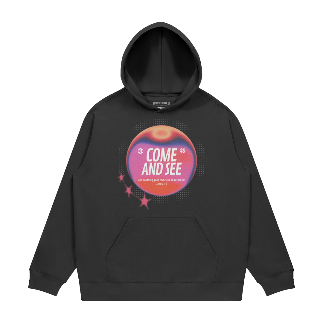 hype4holy come and see heavyweight hoodie black front Black hoodie with a colorful graphic design on a white background