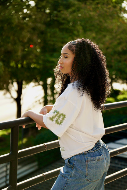 hype4holy christian streetwear unisex t-shirt white color forgiven design model picture side profile | Woman wearing a white oversized shirt with green text, standing outdoors by a railing.
