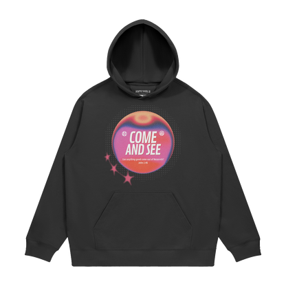 hype4holy come and see heavyweight hoodie black front Black hoodie with a colorful graphic design on a white background