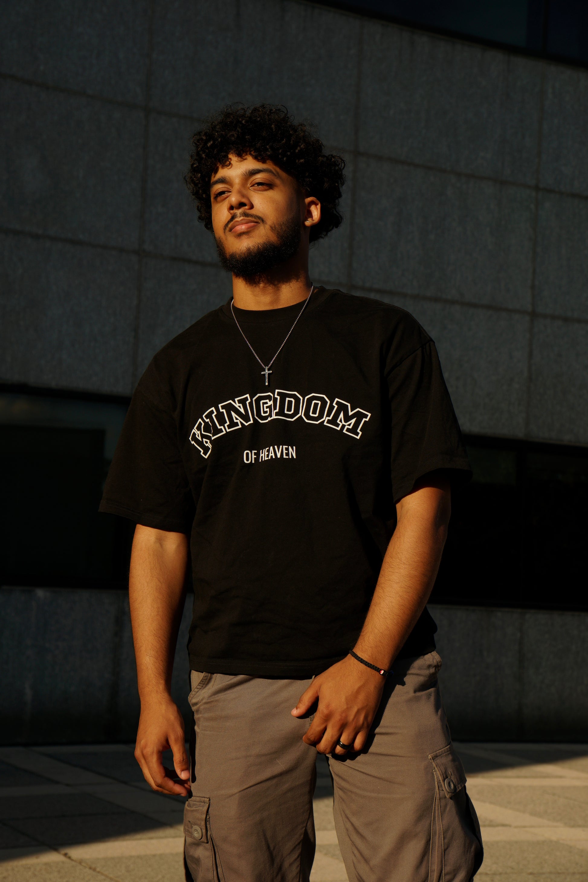 hype4holy premium christian streetwear | Man wearing a black t-shirt with 'Kingdom of Heaven' text, standing outdoors.