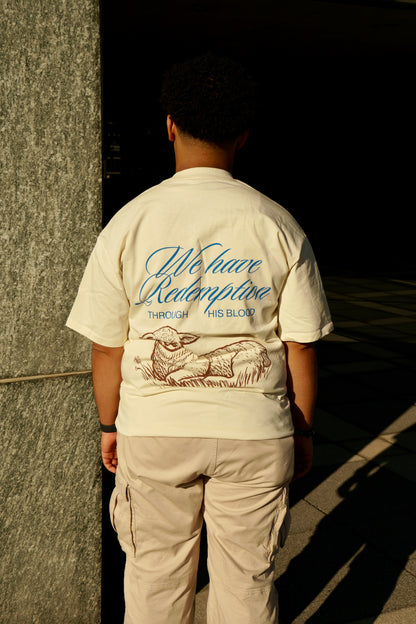 hype4holy christian streetwear t shirt model picture with redemption design in the back and beige pants standing with a brick wall in the background
